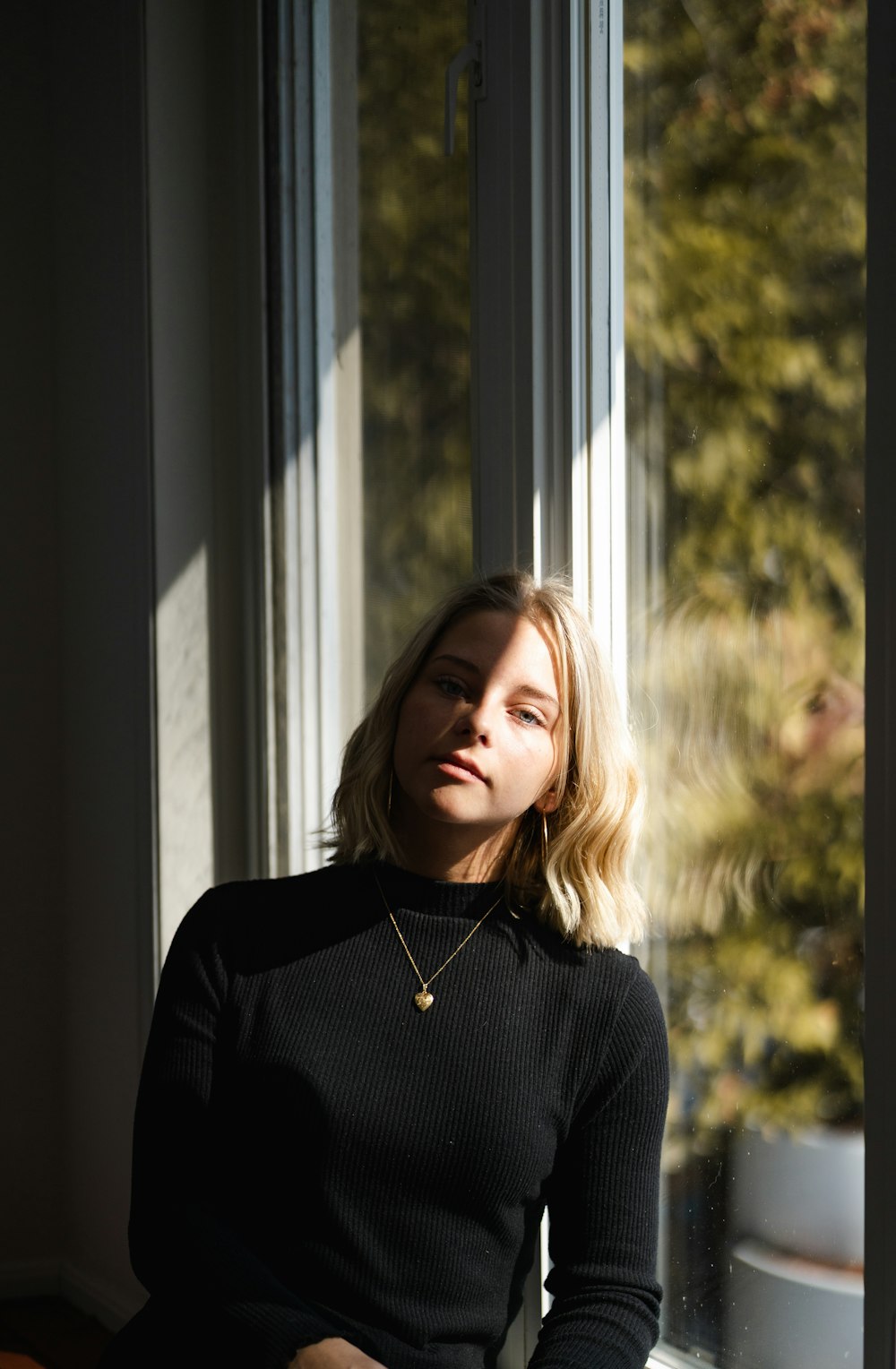 woman in black sweater standing near window