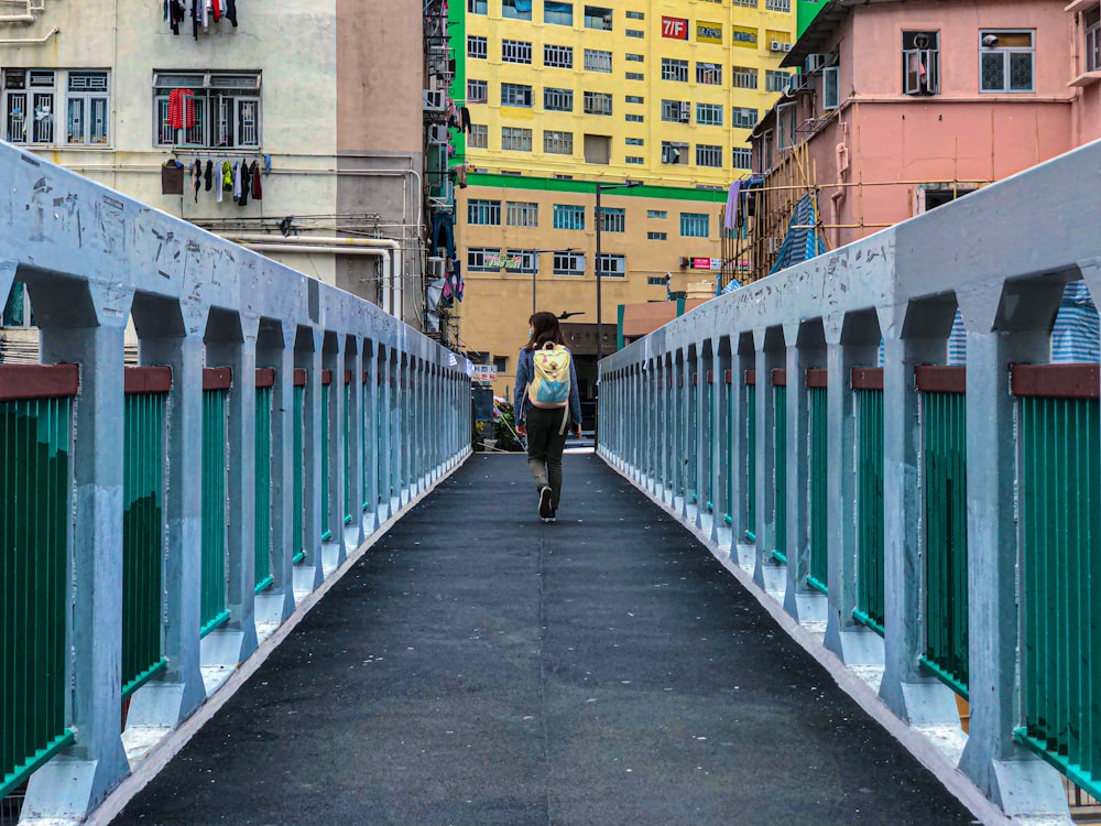 a man walking across a bridge in a city