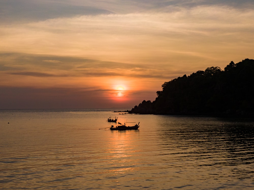 silhouette of people riding boat on sea during sunset