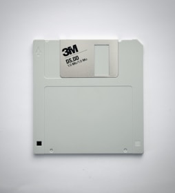 A gray 3.5-inch floppy disk featuring the 3M logo and labeled as DS, DD with a capacity of 1.0 MB. It is set against a plain white background.