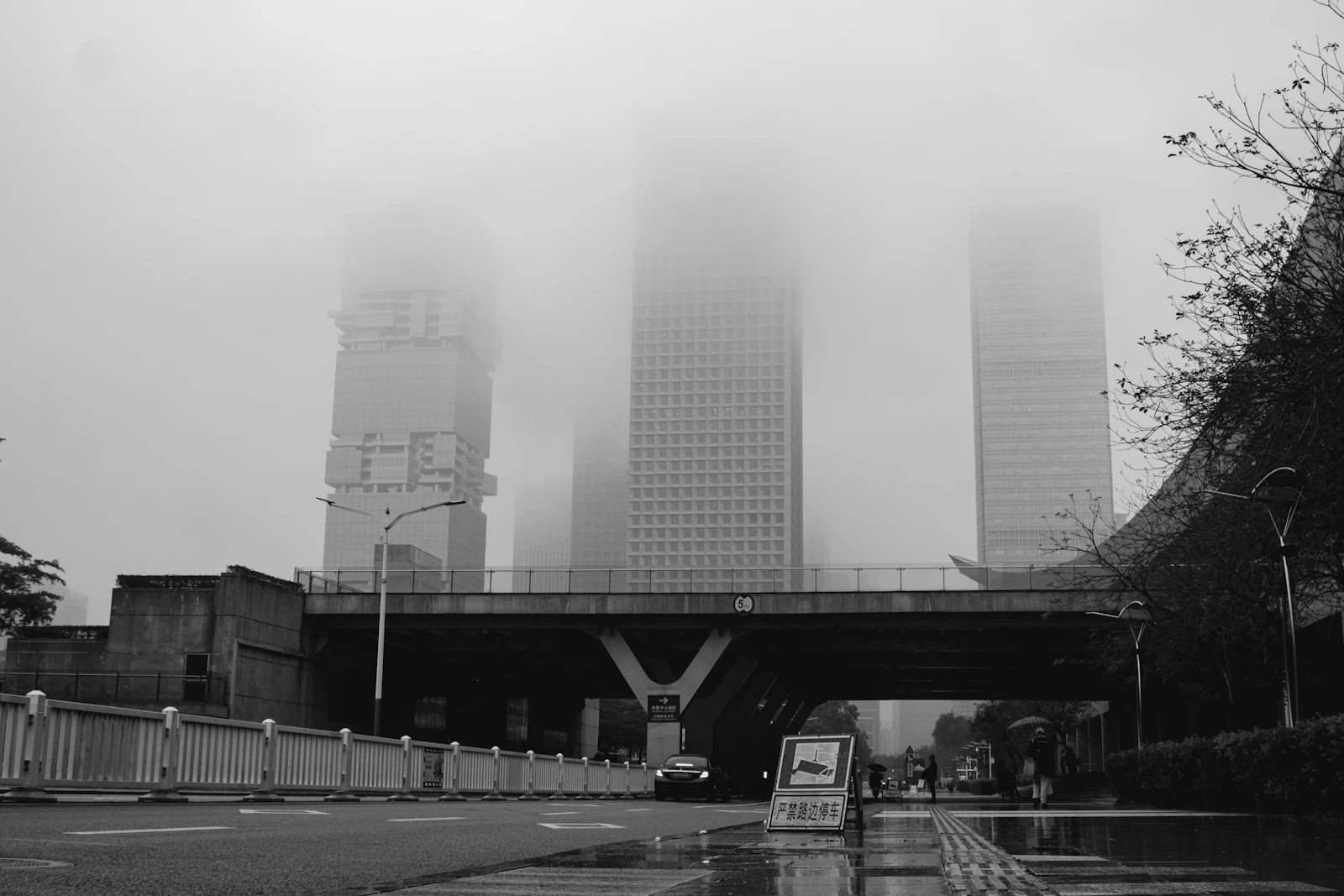 Buildings disappearing into heavy fog, a grayscale cityscape of pressure and obscured horizons
