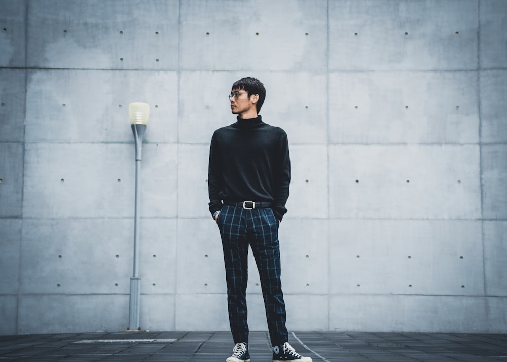 Foto Hombre con camisa negra de manga larga y jeans azules parados en el  piso de concreto gris – Imagen Gris gratis en Unsplash