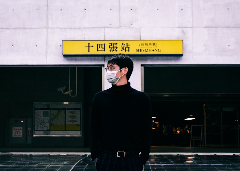 man in black sweater standing near black and yellow building during nighttime