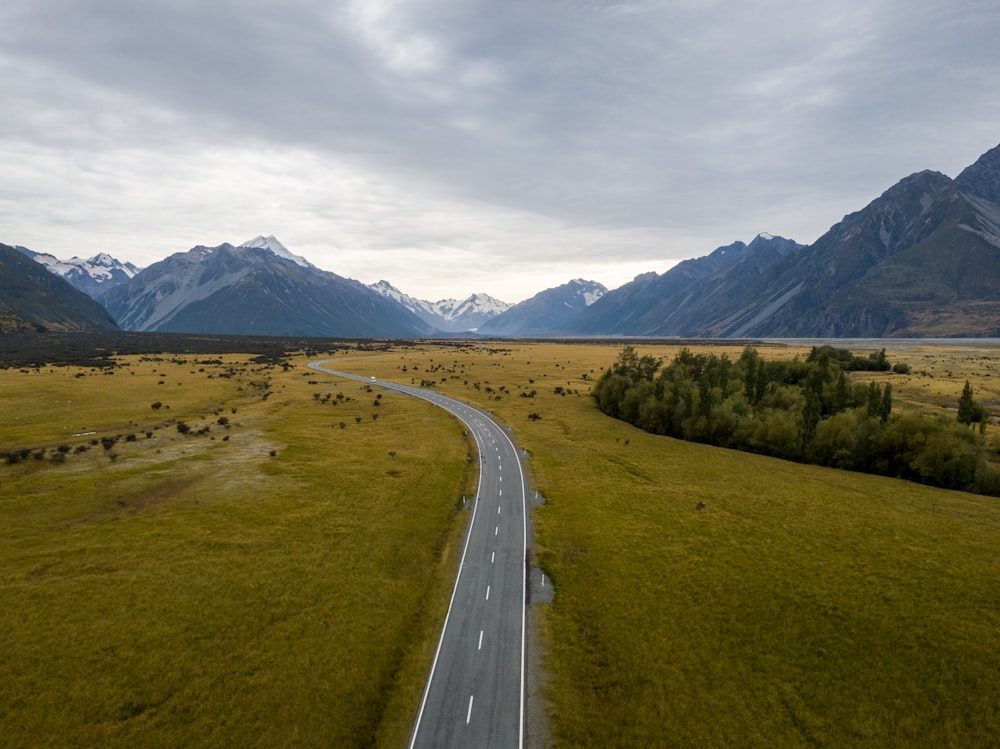 gray concrete road between green grass field during daytime