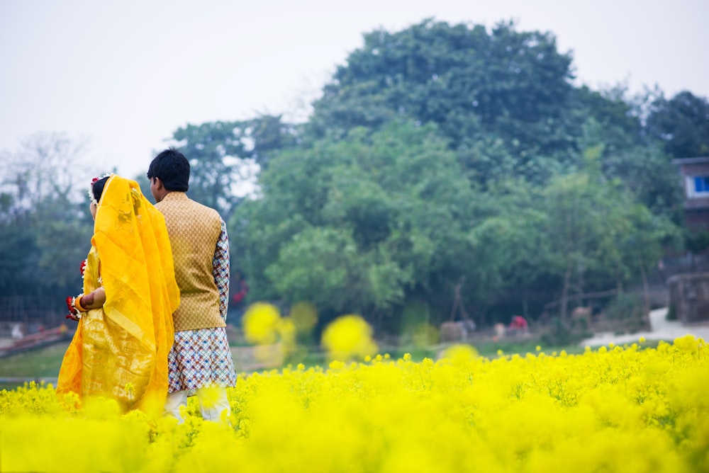 man in yellow dress shirt standing on yellow flower field during daytime