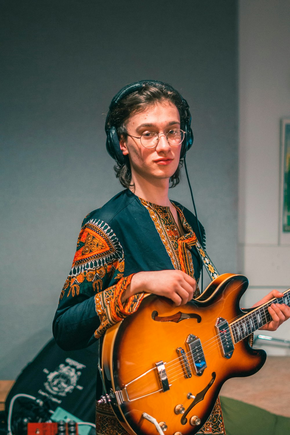 Hombre con camisa de manga larga azul y naranja tocando la guitarra eléctrica marrón