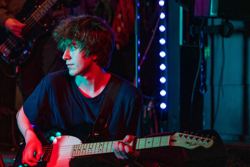 man in black shirt playing electric guitar