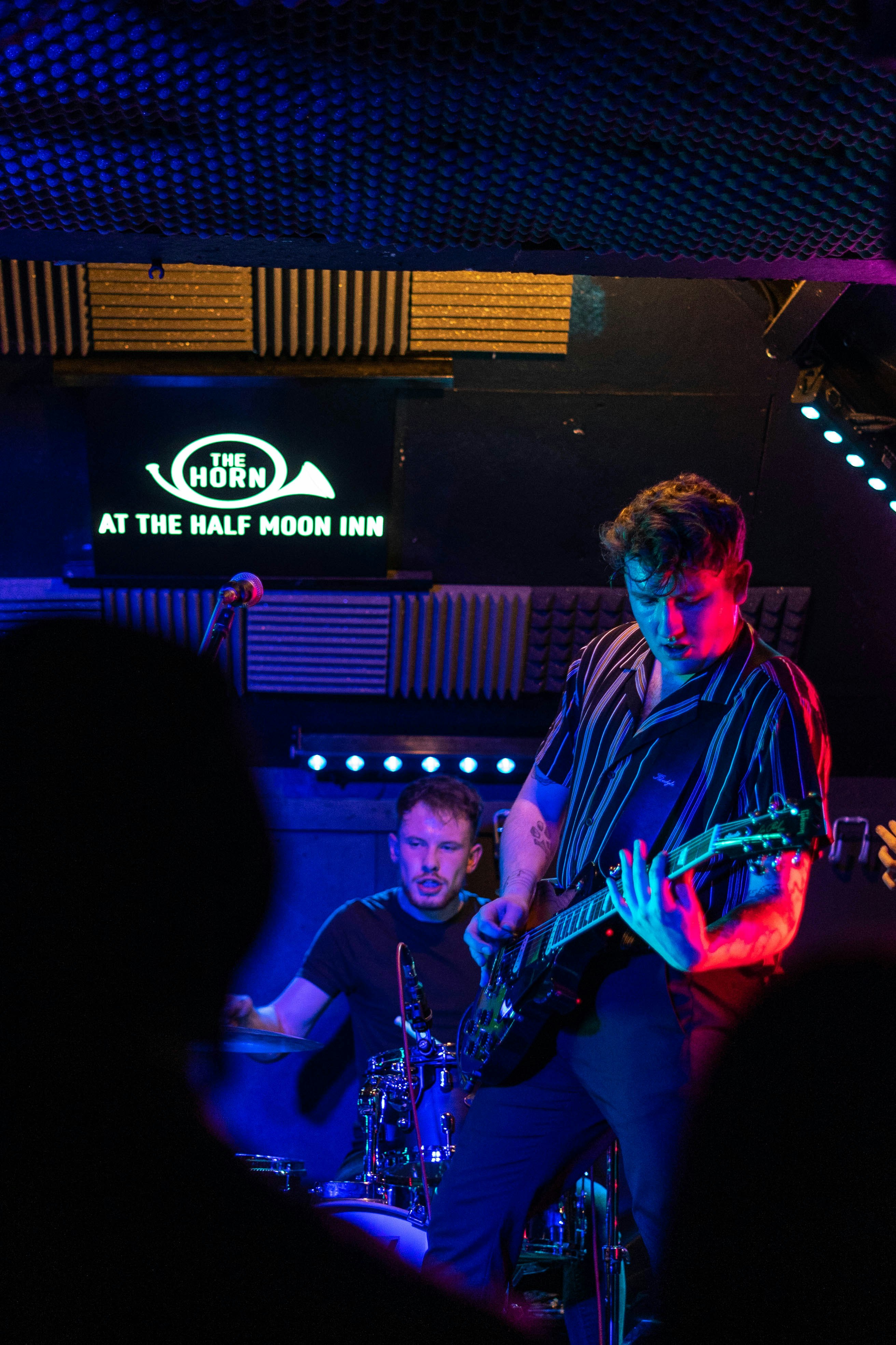 man in blue and white plaid dress shirt playing electric guitar