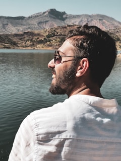 A quiet moment of reflection by a lakeside, with a man looking out over calm water.