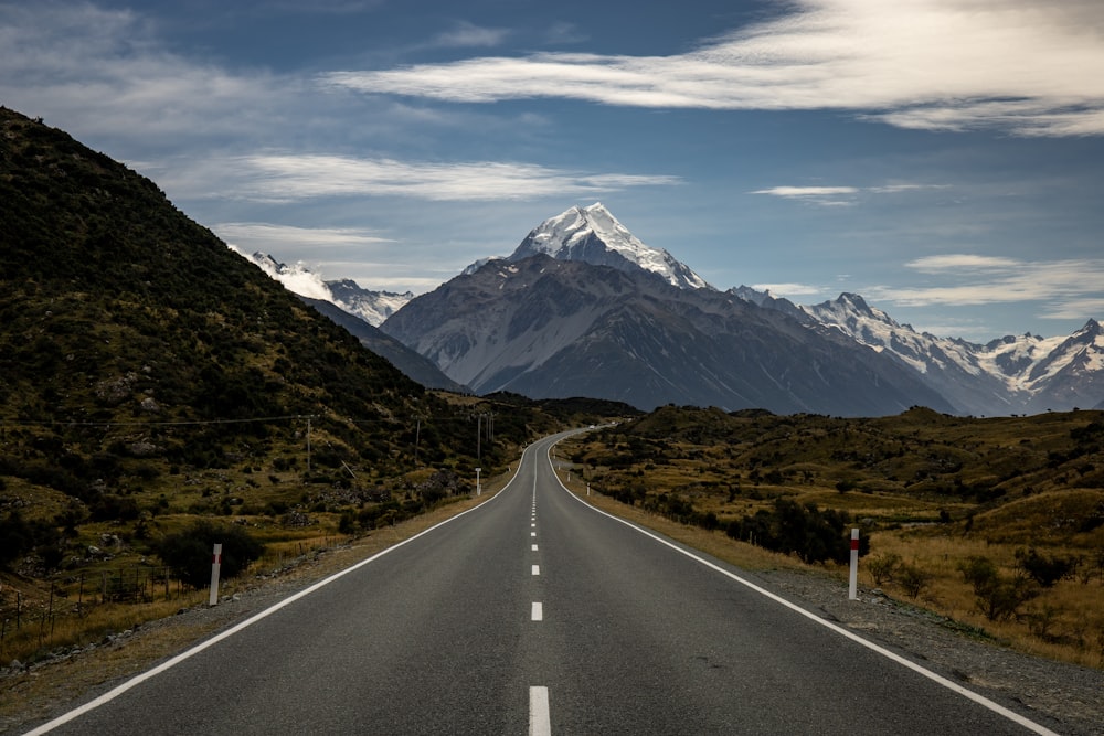 gray concrete road near mountain under white clouds during daytime