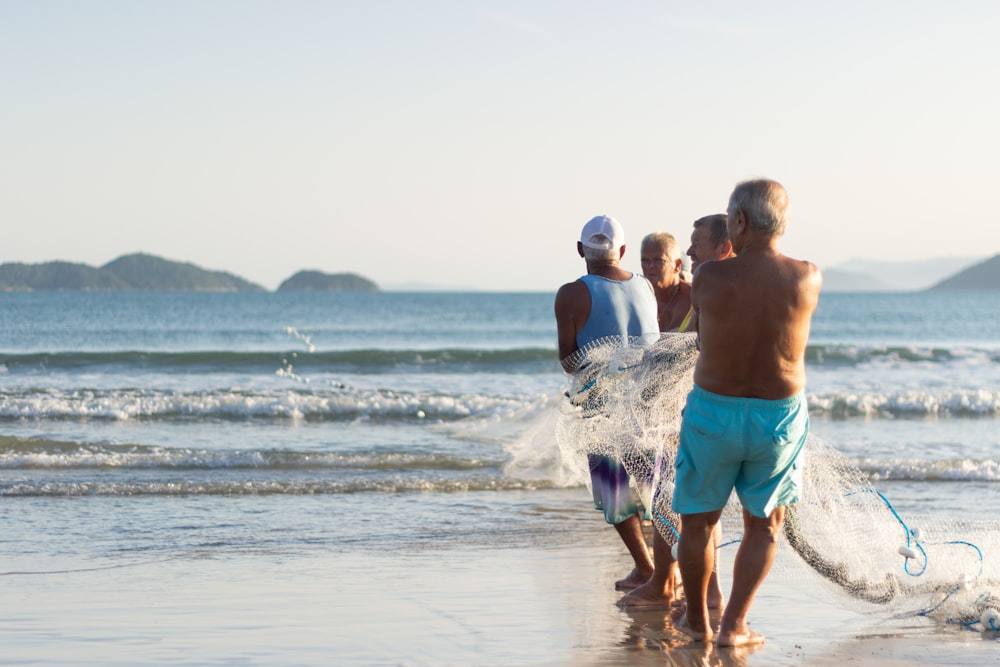 2 men in green shorts walking on beach during daytime