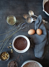 brown egg on white ceramic bowl beside stainless steel spoon