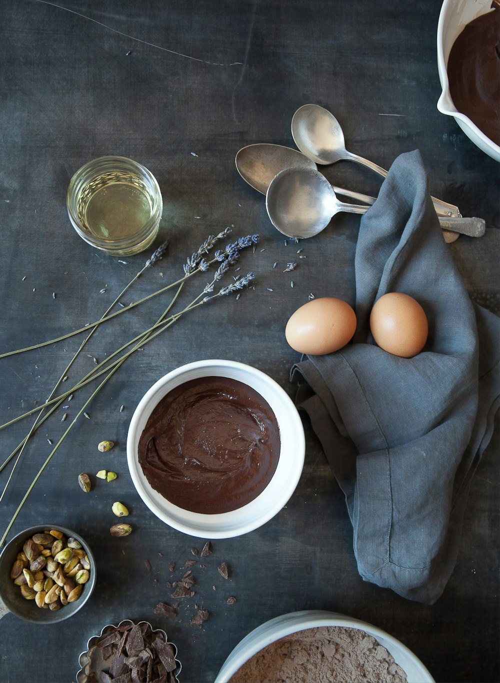 brown egg on white ceramic bowl beside stainless steel spoon