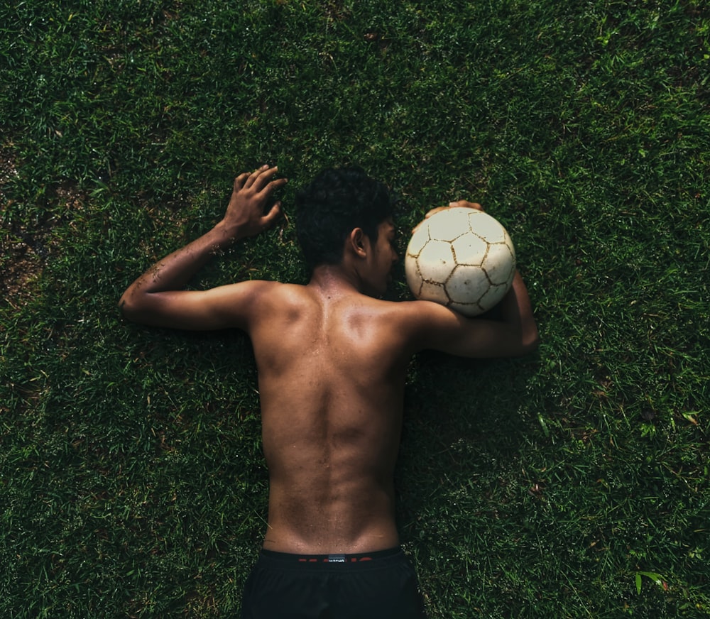 topless man lying on green grass field