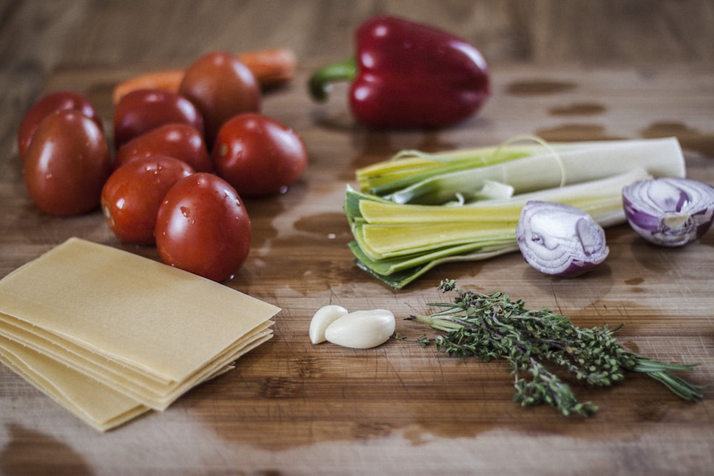 red tomatoes and green leaves on brown wooden table