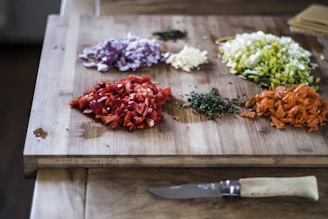 Fresh ingredients like herbs, vegetables, and spices laid out on a wooden board.