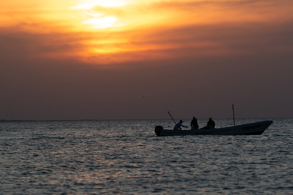 silhouette of people riding on boat during sunset