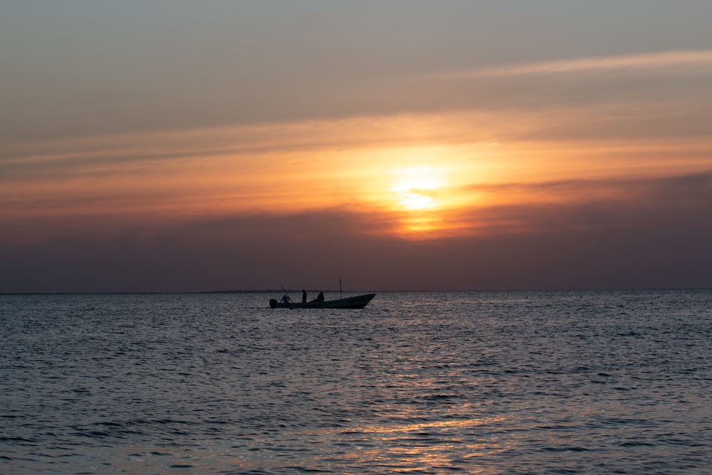 silhouette of boat on sea during sunset