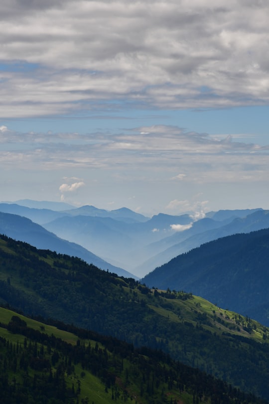 green mountains under white clouds during daytime in Manali India