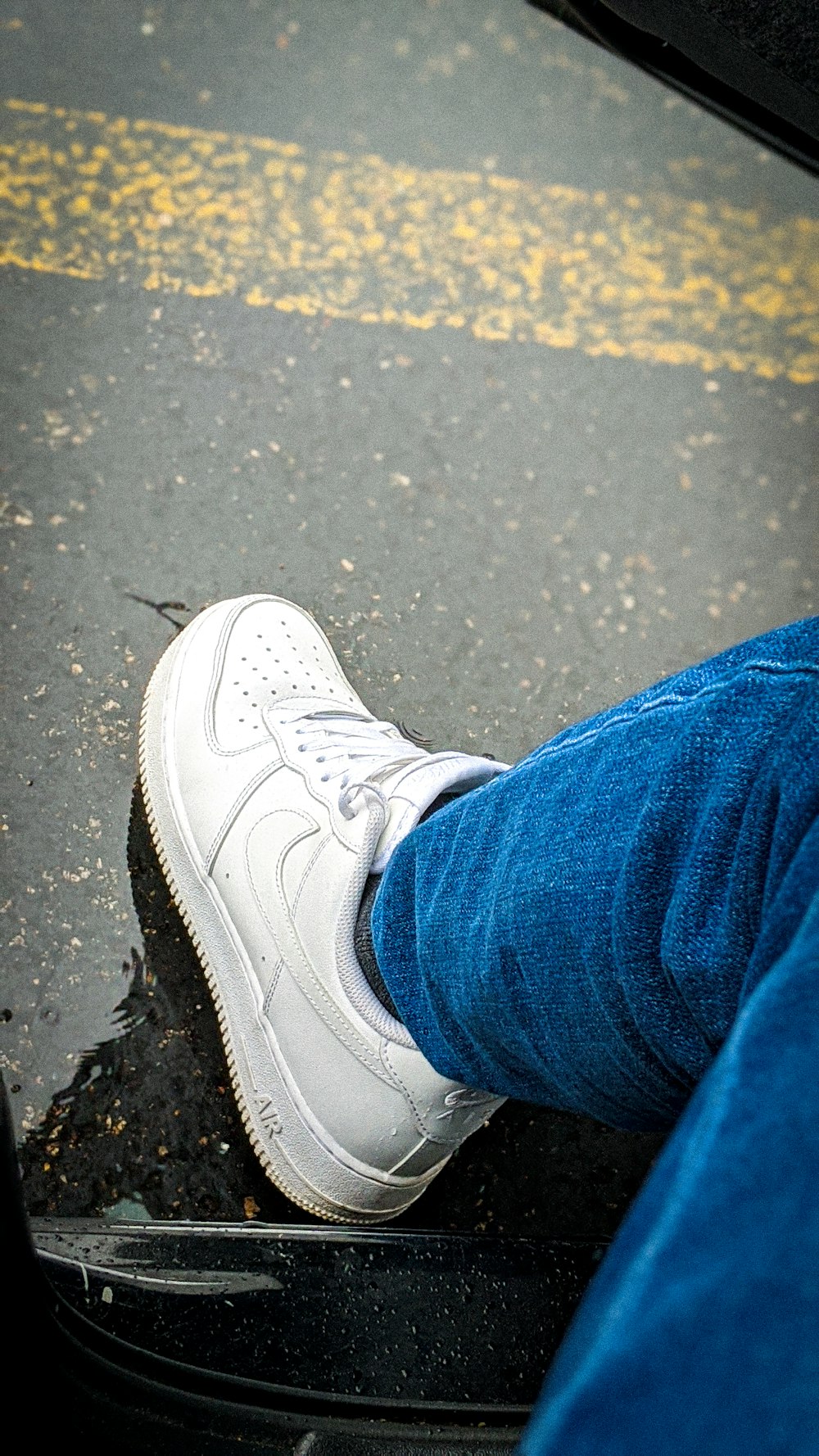 Persona con jeans de mezclilla azules y zapatillas Nike blancas