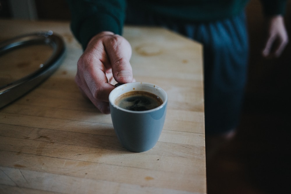 person holding white ceramic mug with coffee