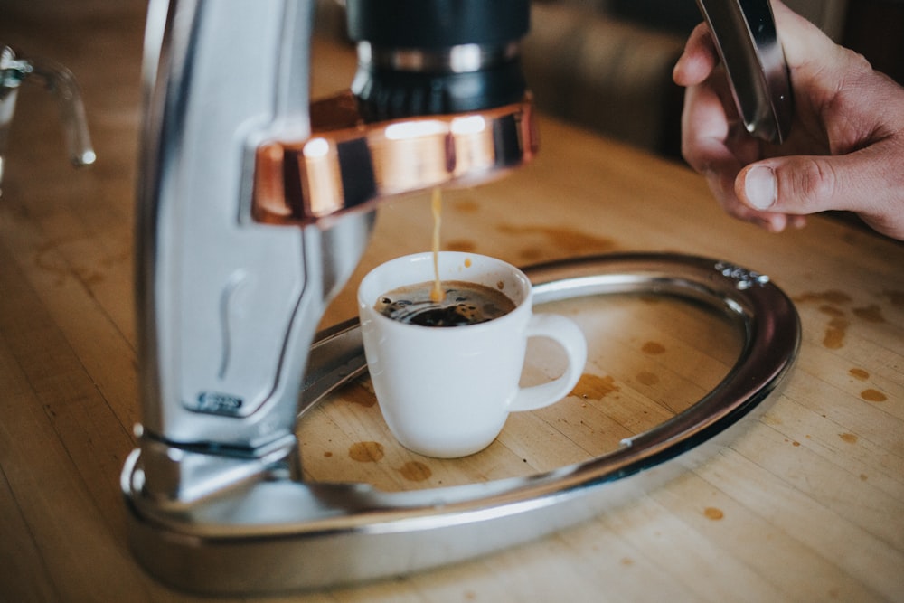 person pouring coffee on white ceramic mug