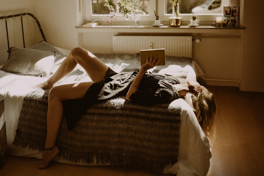 woman in black dress lying on bed