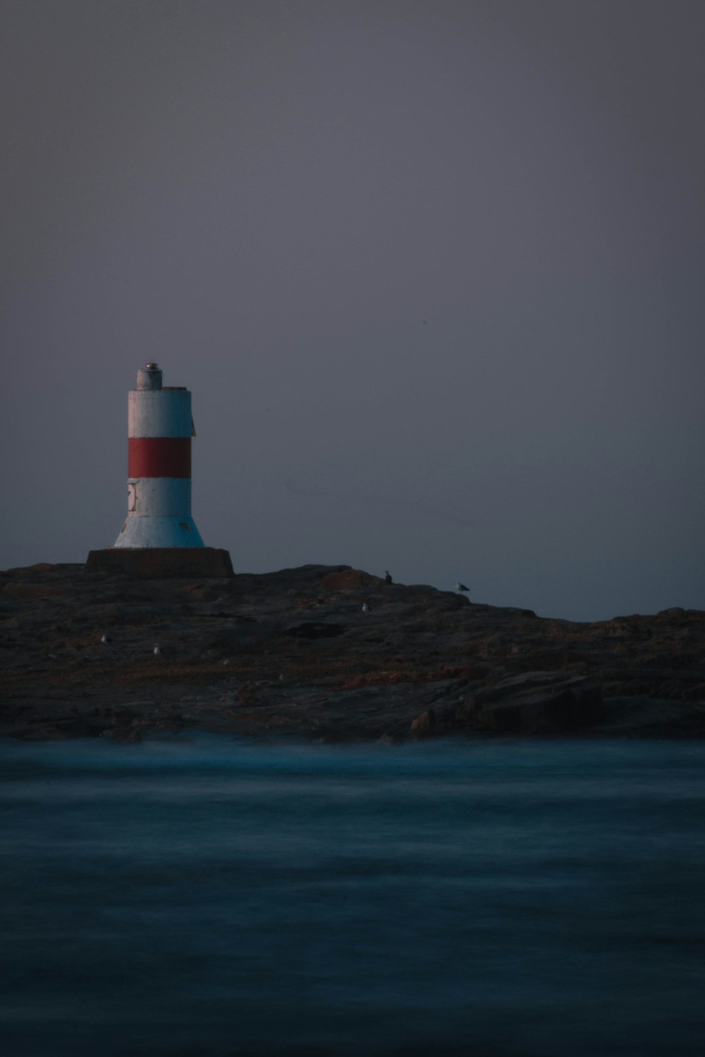 white and red lighthouse on brown rock formation