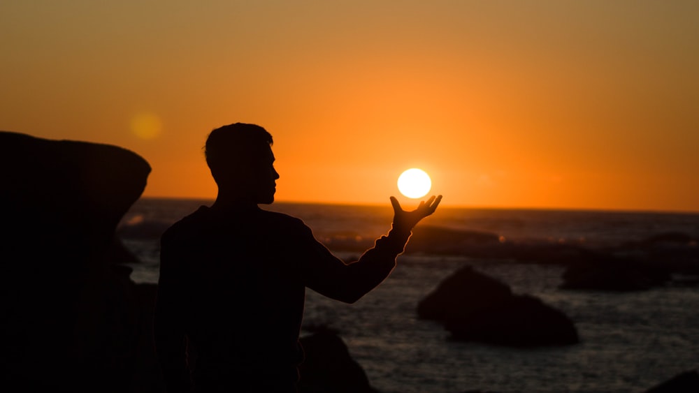silhouette of man holding sun