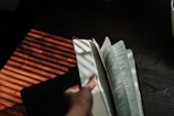 Close-up of hands flipping through pages of a beautifully designed anthology book.