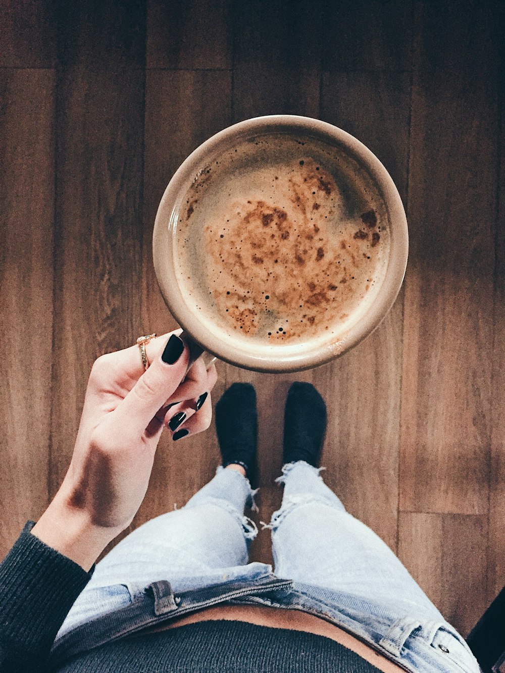 person holding white ceramic mug with brown liquid