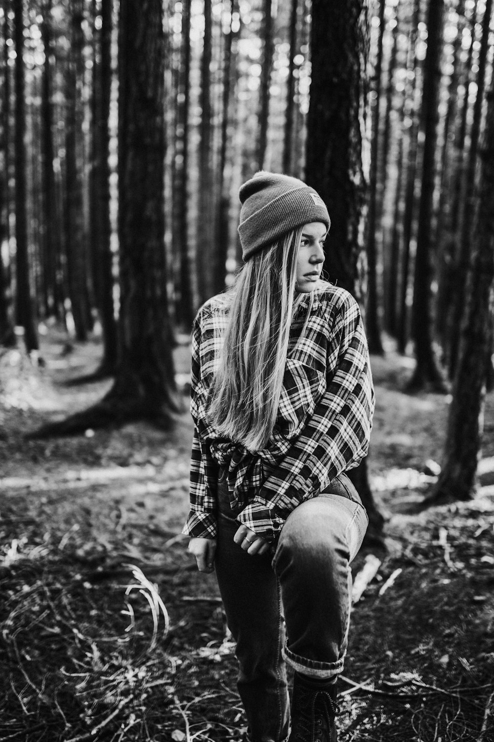 grayscale photo of woman in plaid shirt and denim jeans sitting on ground
