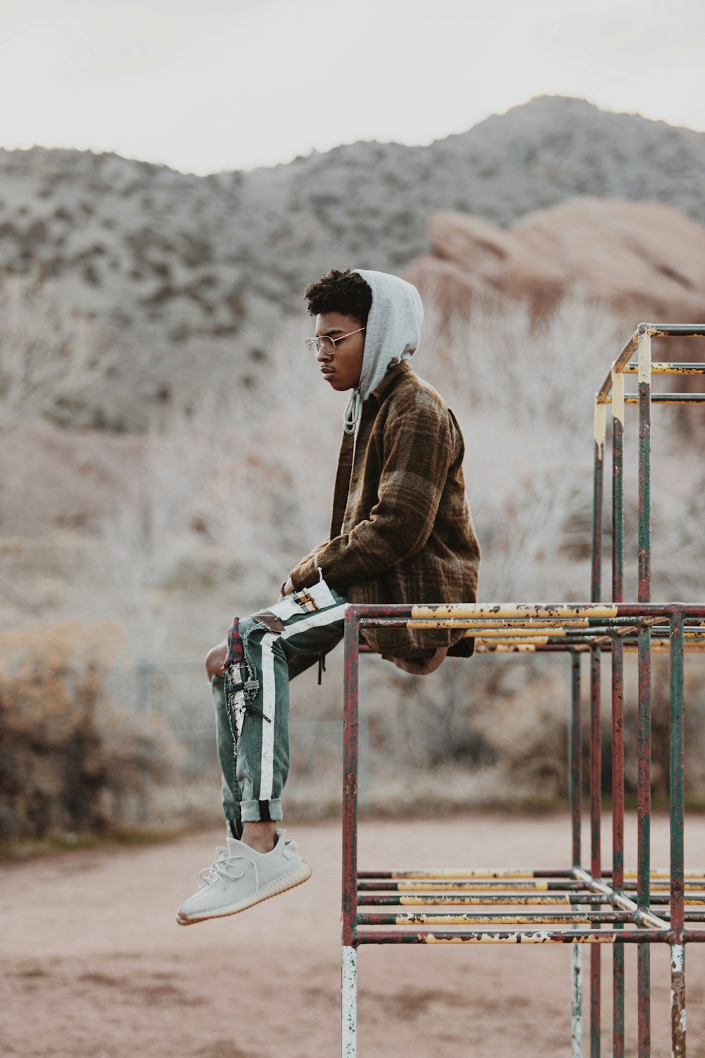 man in brown jacket and gray pants standing on red metal ladder during daytime