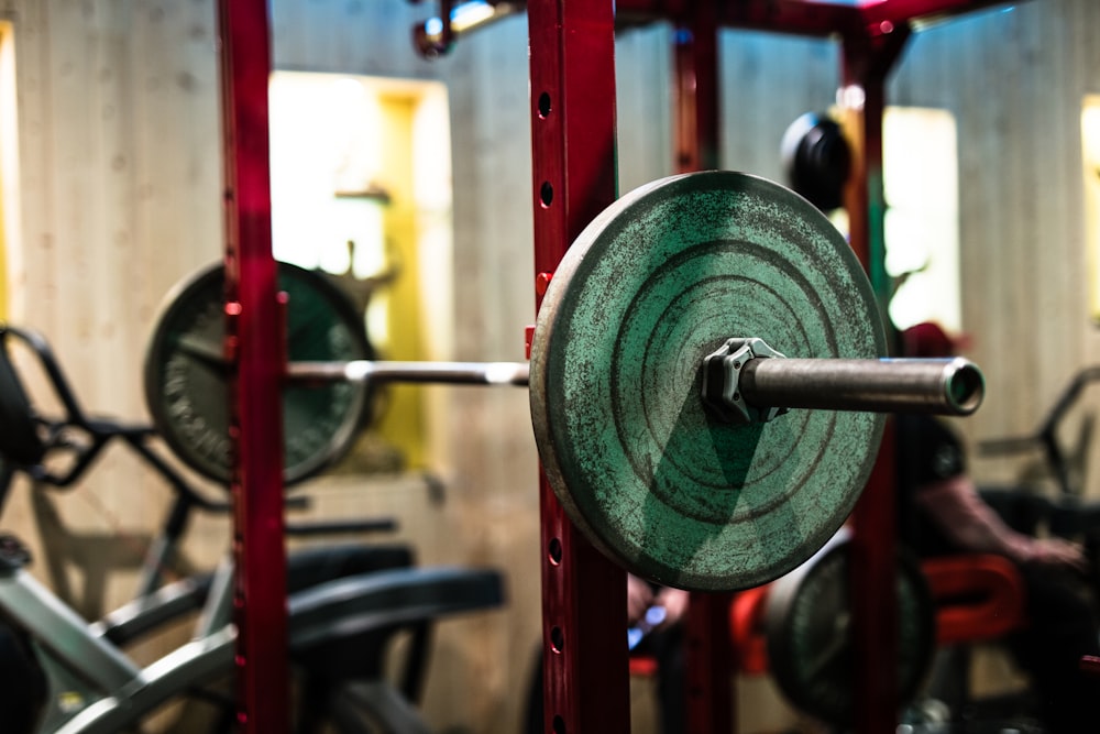 green and black barbell on black steel stand