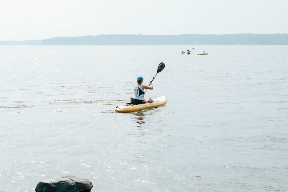 man in blue shirt riding yellow kayak on body of water during daytime