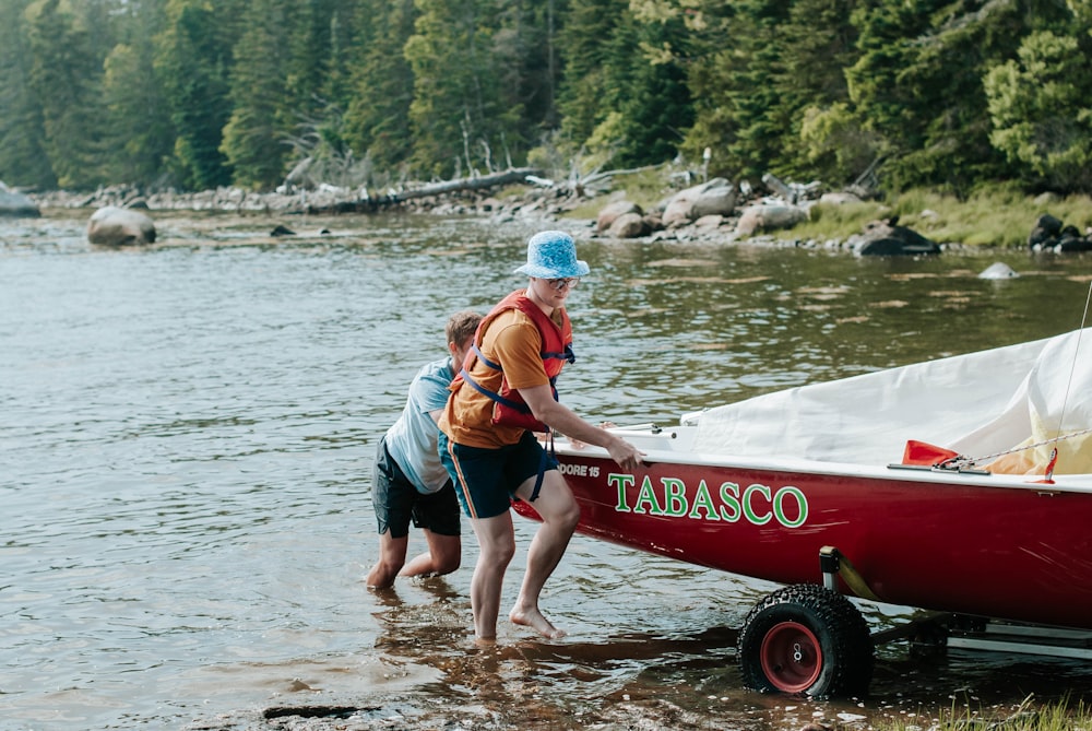 man in blue shorts holding a girl in red shirt on a red and white boat