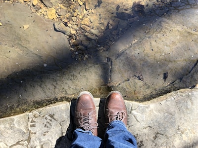 Close-up of a rugged fishing shoe on a rocky riverbank with water splashing nearby