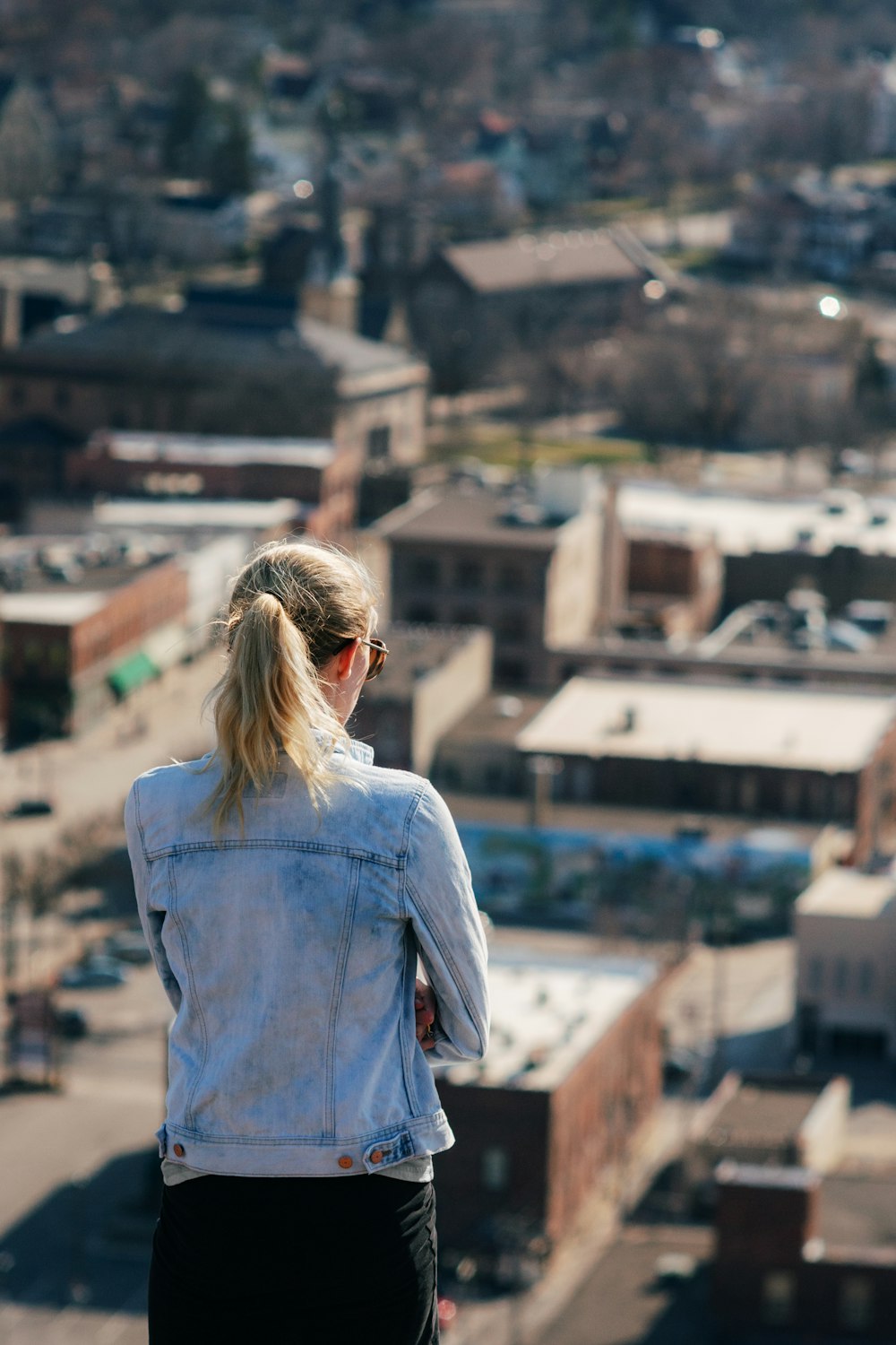 woman in blue denim jacket standing on top of building during daytime