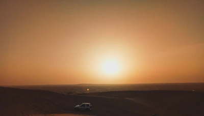 A cinematic golden hour shot of a man standing beside his van overlooking a desert landscape.