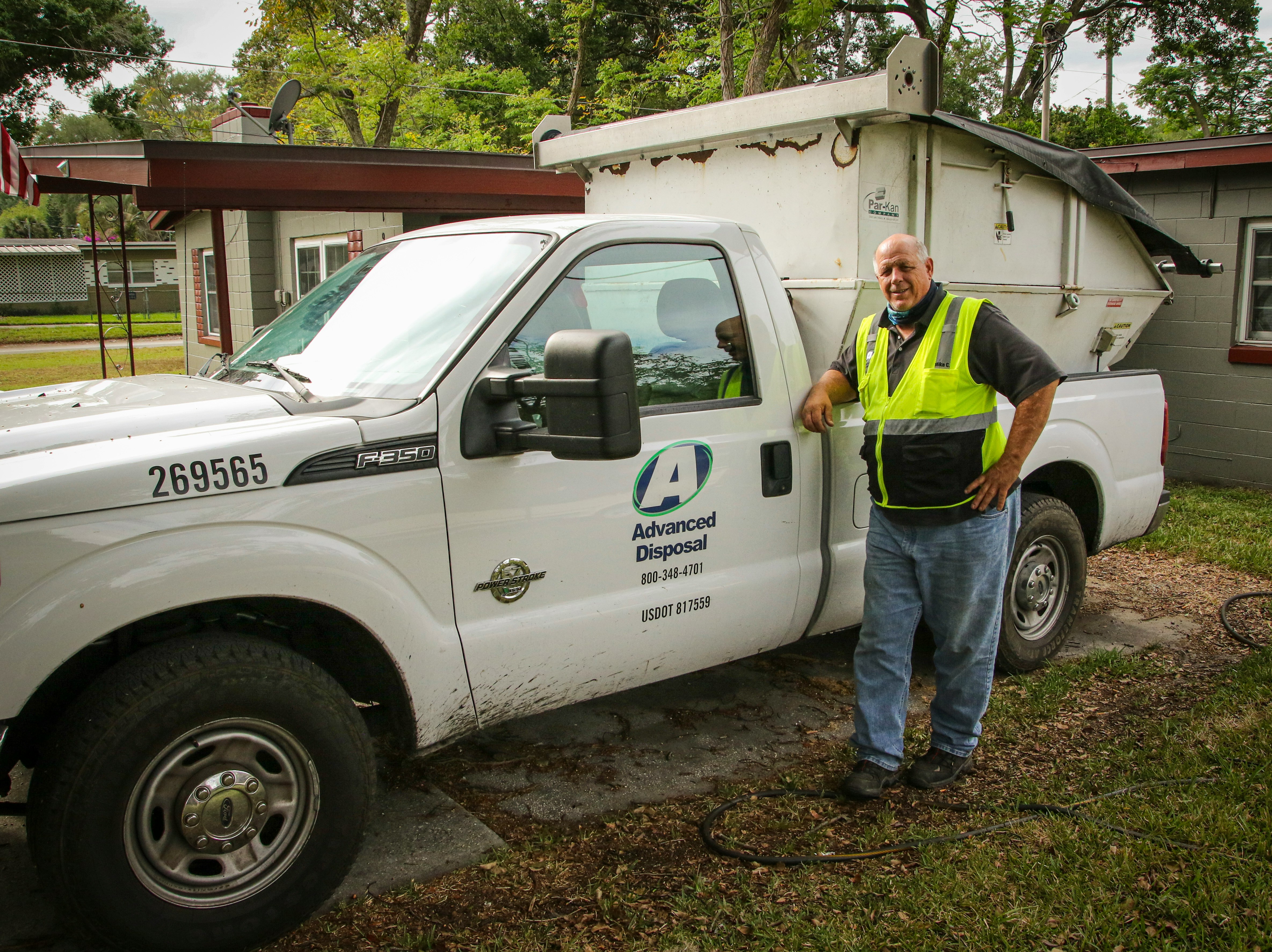 man in yellow shirt standing beside white crew cab pickup truck