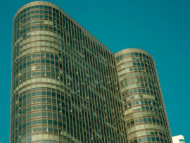 A high-rise commercial property with elegant glass facades reflecting the blue sky.