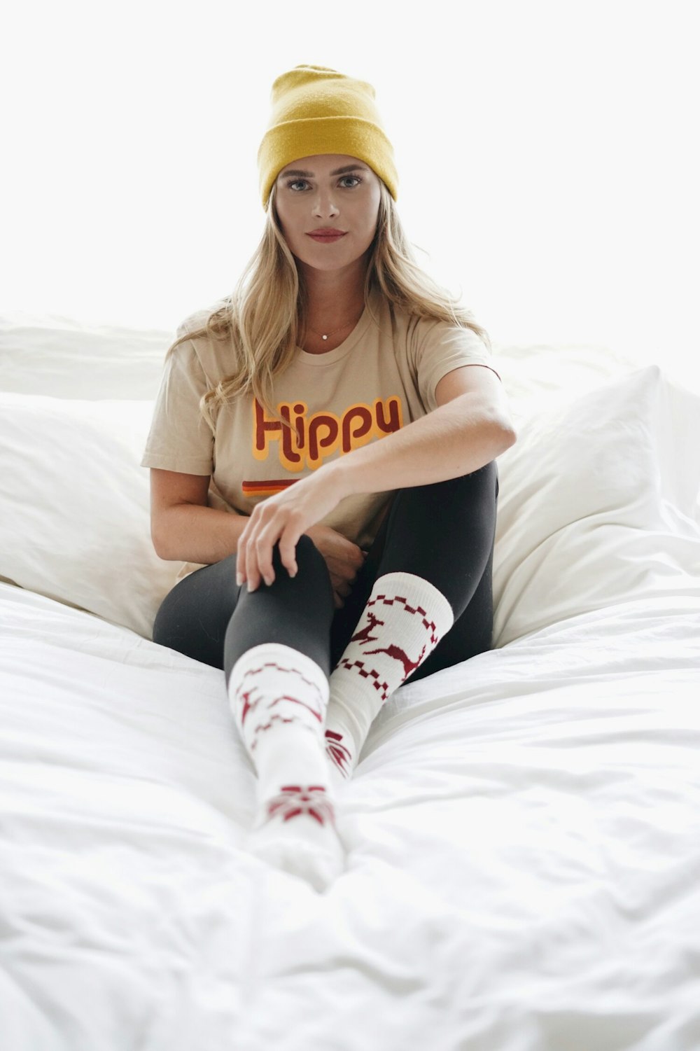 woman in brown crew neck t-shirt and black pants sitting on white bed