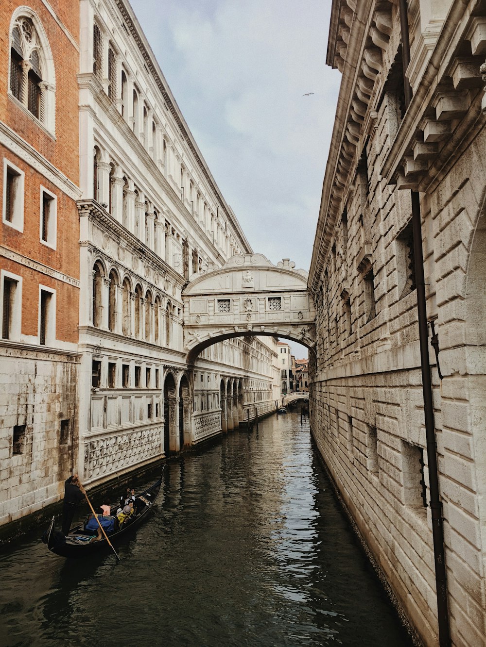 boat on river between concrete buildings during daytime