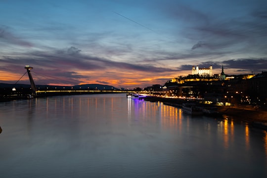 body of water near city buildings during night time in Bratislava Slovakia