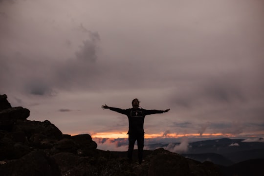 man standing on rock formation under cloudy sky during daytime in Mount Wellington Australia