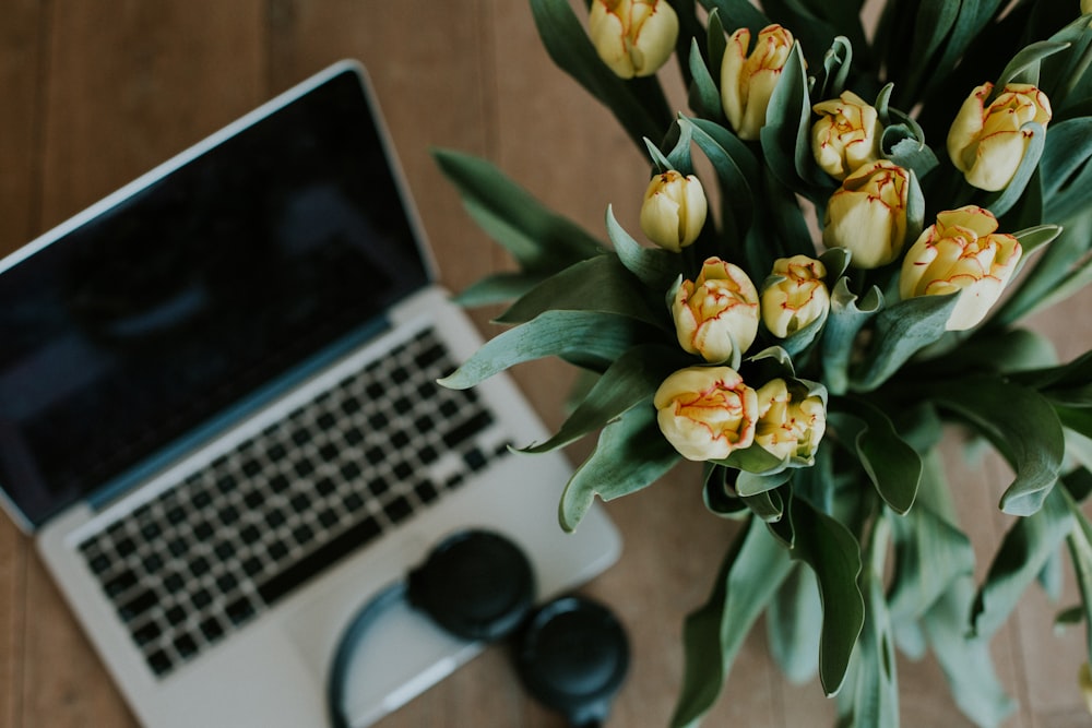 white and yellow flower bouquet beside macbook pro