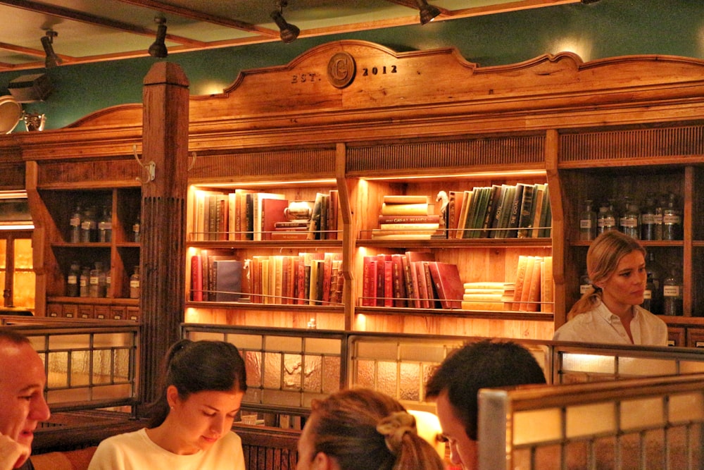 people sitting on chair in front of book shelf