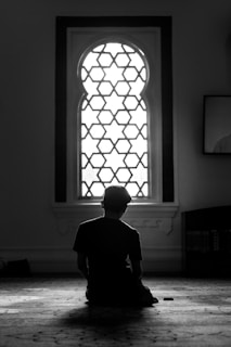 An elegant home interior showing a person seated in meditation posture near a window with beige curtains.
