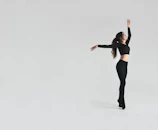 A dramatic black-and-white portrait of a dancer mid-motion against a dark backdrop.