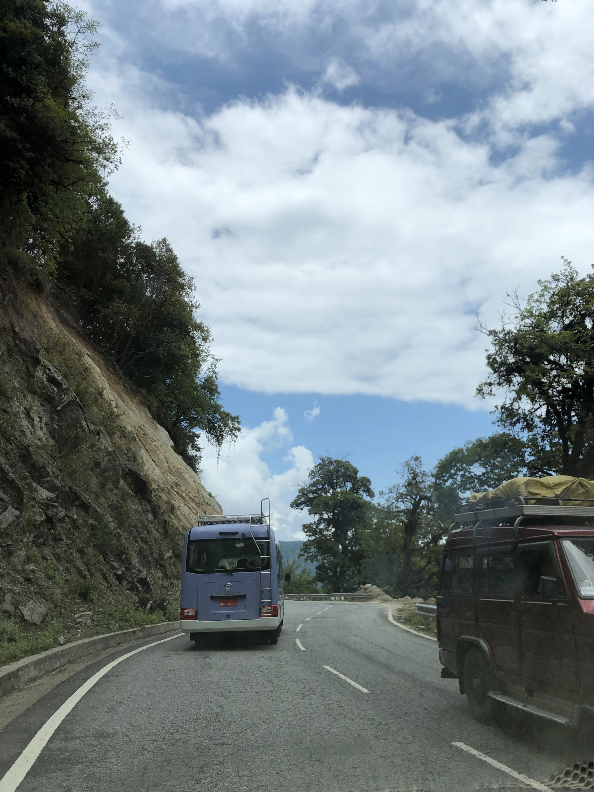 A scenic coastal road along the Caribbean Sea near Santa Marta, with a comfortable minibus driving under a bright blue sky.